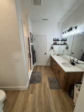 Bathroom with double vanity, a shower stall, light wood finished floors, and a textured ceiling