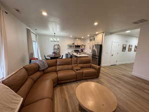 Living room with a textured ceiling, light wood-style flooring, and a chandelier
