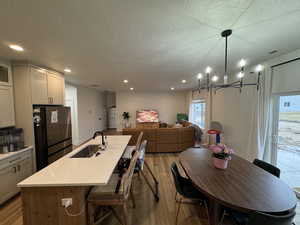 Dining room with light wood finished floors, a textured ceiling, and suspended lighting