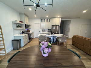Dining space featuring light wood-type flooring, a textured ceiling, and suspended lighting