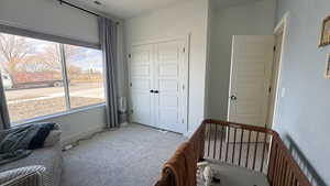 Bedroom with a closet, carpet flooring, and a crib