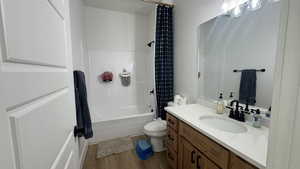 Full bathroom with vanity, shower / bath combo with shower curtain, and dark wood-type flooring