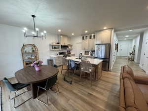 Dining area featuring light wood-style flooring, a chandelier, and a textured ceiling