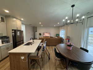 Kitchen featuring open floor plan, freestanding refrigerator, a breakfast bar area, light wood finished floors, and a center island with sink