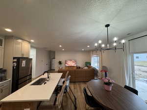 Dining room with wood finished floors, a textured ceiling, and suspended lighting
