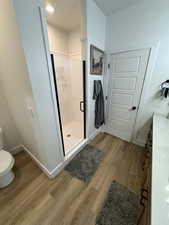 Full bath with a shower stall, vanity, and light wood-style flooring