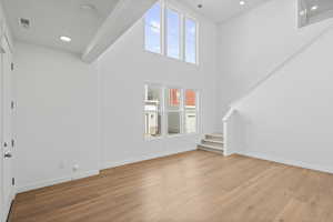 Unfurnished living room with a high ceiling, light wood-style floors, and recessed lighting