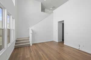 Unfurnished living room featuring a high ceiling and light wood-style floors