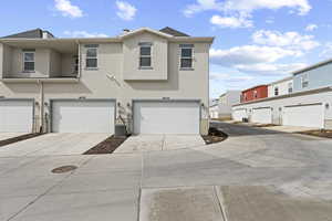 Traditional-style home with stucco siding, a garage, and driveway