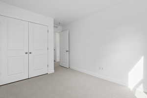 Unfurnished bedroom with light colored carpet and a closet
