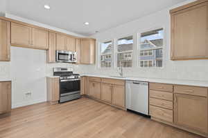 Kitchen featuring stainless steel appliances, light wood-style flooring, light wood finish cabinetry, tasteful backsplash, and recessed lighting