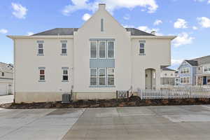 Back of property featuring a shingled roof, a fenced front yard, and stucco siding