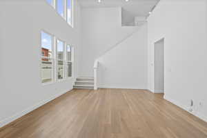 Unfurnished living room featuring a high ceiling and light wood finished floors
