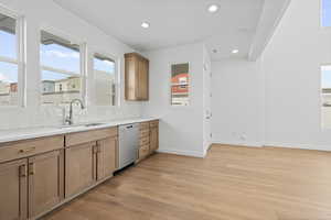Kitchen featuring light wood-type flooring, light stone counters, recessed lighting, stainless steel dishwasher, and tasteful backsplash