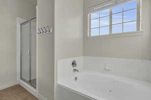 Bathroom featuring a stall shower, a garden tub, and light tile patterned floors