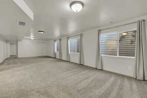 Unfurnished room featuring light colored carpet and a textured ceiling