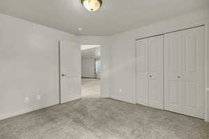 Unfurnished bedroom featuring light colored carpet and a closet
