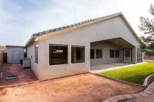 Rear view of house with a patio area, stucco siding, a sunroom, and a tile roof