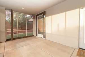 Unfurnished sunroom with concrete flooring, expansive windows, and recessed lighting