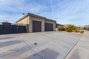 View of home's exterior featuring a gate, stucco siding, concrete driveway, a garage, and a tiled roof