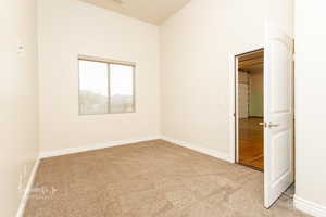 Unfurnished bedroom with light carpet and baseboards