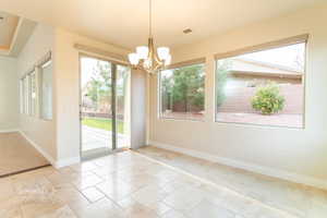 Unfurnished dining area with stone tile floors, suspended lighting, and healthy amount of natural light