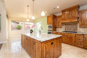 Kitchen featuring wood finish cabinets, light stone counters, and stone tile flooring