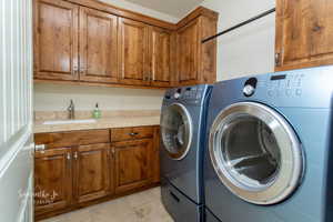 Laundry area with cabinet space, separate washer and dryer, and light tile patterned flooring