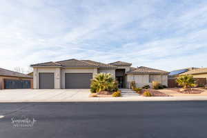 View of front of house with an attached garage, driveway, stucco siding, and a tile roof