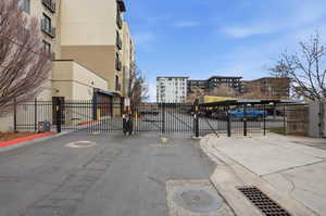 View of asphalt street with a gate, a gated entry, and curbs