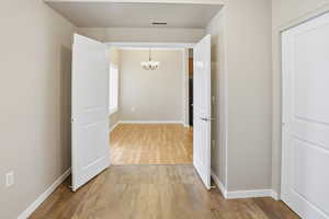Hall with suspended lighting and light wood-style flooring