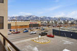 View of asphalt road featuring a mountain view, curbs, sidewalks, and street lighting