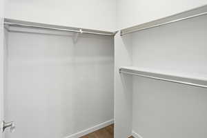 Walk in closet with dark wood-style floors