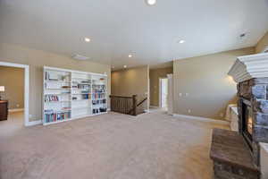 Unfurnished room featuring an upstairs landing, a fireplace, light colored carpet, and recessed lighting