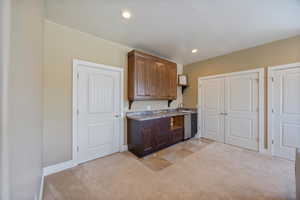 Kitchen with recessed lighting, dark wood finish cabinetry, and light carpet
