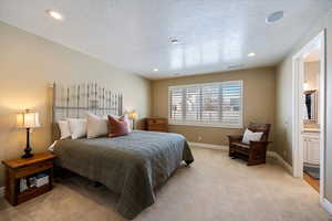 Bedroom featuring light carpet, ensuite bath, a textured ceiling, and recessed lighting