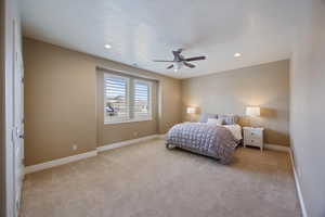 Bedroom with light colored carpet, ceiling fan, recessed lighting, and a textured ceiling