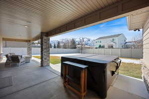 Fenced backyard with a mountain view, a patio, and a hot tub