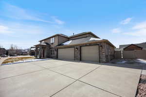 View of front of house featuring an attached garage, a gate, driveway, board and batten siding, and stone siding
