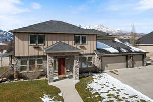 View of front of home with a mountain view, board and batten siding, stone siding, and a garage