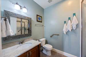 Full bathroom with vanity, dark tile patterned flooring, and a shower