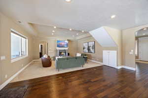 Living area with arched walkways, wood-type flooring, recessed lighting, a fireplace, and a tray ceiling