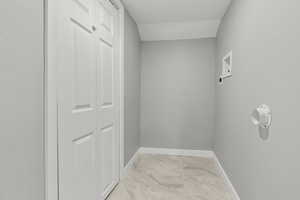 Laundry area with baseboards and light marble finish floors