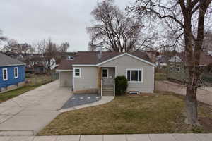 Bungalow-style house featuring a shingled roof, a front lawn, and concrete driveway
