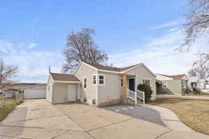Single story home featuring an outdoor structure, a detached garage, and roof with shingles