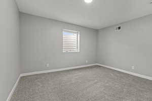 Carpeted spare room featuring baseboards