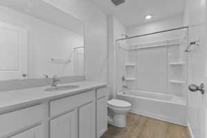 Bathroom featuring light wood-style floors, vanity, and shower / tub combination