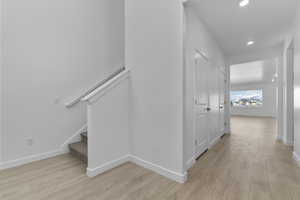 Hall with light wood finished floors and recessed lighting