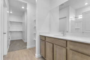 Full bath featuring recessed lighting, a walk in closet, light wood-style flooring, vanity, and a shower