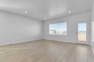 Empty room with light wood finished floors and recessed lighting